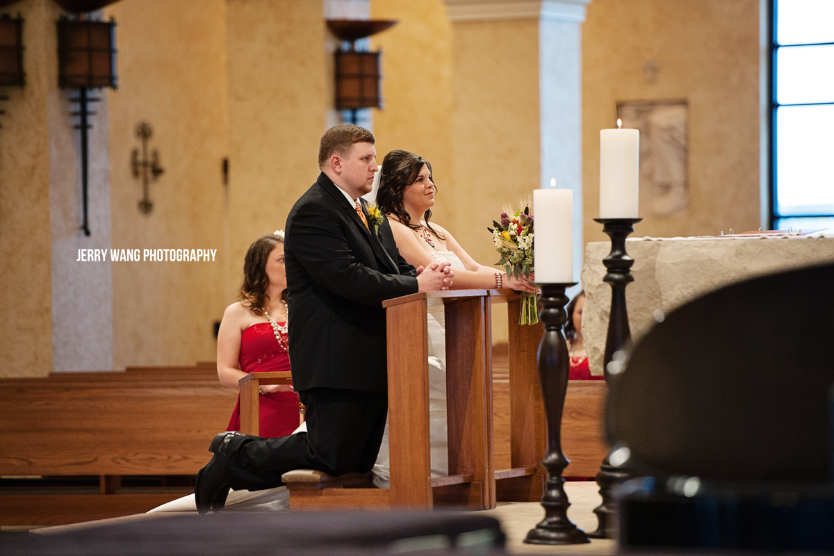 The bride and groom kneeling at the altar